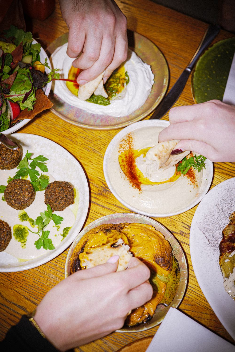 Handen die falafel en hummus delen aan tafel